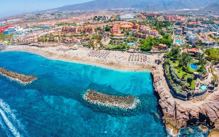 Aerial view of a beautiful beach and a luxurious resort showcasing sandy shores and clear blue water.