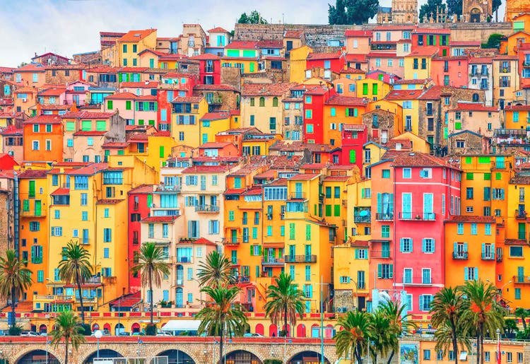 Colorful buildings stacked closely together in Menton, a mix of yellow and red houses that reflect the city's unique architectural style.